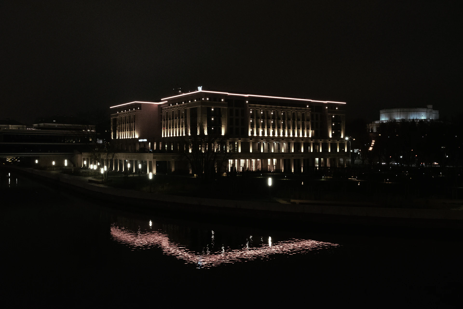 Hotel lit up at night and reflected in dark water, hotel payment processing by Niche Payments
